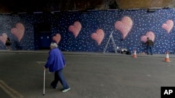 Australian street artist James Cochran, also known as Jimmy C, works, March 26, 2018, on his mural with eight hearts, each representing one of the eight victims of the attack that took place on London Bridge and around Borough Market in 2017.