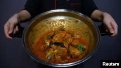 Seorang chef menunjukkan sepanci rendang ayam di sebuah restoran di Cyberjaya, Selangor, Malaysia, 4 April 2018.