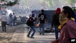 A man uses a slingshot as protesting teachers battle all day with riot police in the state of Oaxaca, near the town of Nochixtlan, Mexico, Sunday, June 19, 2016.