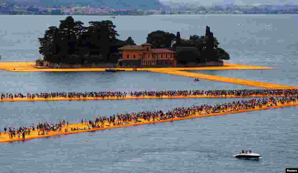 People walk on the installation 'The Floating Piers' by Bulgarian-born artist Christo Vladimirov Yavachev, known as Christo, at the installation's last weekend near Sulzano, northern Italy, July 2, 2016.