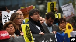 Catalonia's former regional president Carles Puigdemont, center, holds a banner with others during a protest in front of the European Commission headquarters in Brussels, Oct. 15, 2019. 