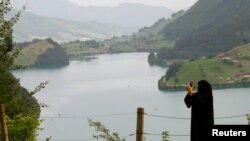 FILE - A woman wearing a niqab takes a picture from a lookout above lake Lungenersee at the Bruenigpass mountain pass road, Switzerland, Aug. 3, 2017.