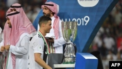 Pemain depan Juventus, Cristiano Ronaldo, berjalan melintasi trofi Supercoppa Italiana, setelah final melawan AC Milan di Stadion King Abdullah Sports City di Jeddah, 16 Januari 2019.