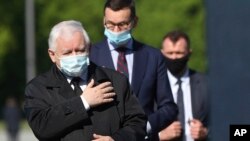 Poland's ruling party leader Kaczynski, left, and PM Morawiecki, center, pray at the monument to the late President Lech Kaczynski, the party leader's twin, killed with 95 others in a plane crash April 10, 2010 in Russia, in Warsaw, May 10, 2020.