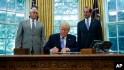 President Donald Trump, joined by Vice President Mike Pence, left, and Secretary of Health and Human Services Alex Azar, right, signs a $4.6 billion aid package at the White House, July 1, 2019.