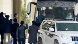 Workers wave to the team of experts from the World Health Organization who ended their quarantine and prepare to leave the quarantine hotel by bus in Wuhan in central China's Hubei province on Thursday, Jan. 28, 2021. (AP Photo/Ng Han Guan)