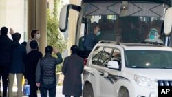 Workers wave to the team of experts from the World Health Organization who ended their quarantine and prepare to leave the quarantine hotel by bus in Wuhan in central China's Hubei province on Thursday, Jan. 28, 2021. (AP Photo/Ng Han Guan)