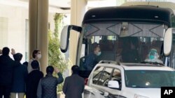 Workers wave to the team of experts from the World Health Organization who ended their quarantine and prepare to leave the quarantine hotel by bus in Wuhan in central China's Hubei province on Thursday, Jan. 28, 2021. (AP Photo/Ng Han Guan)