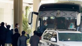 Workers wave to the team of experts from the World Health Organization who ended their quarantine and prepare to leave the quarantine hotel by bus in Wuhan in central China's Hubei province on Thursday, Jan. 28, 2021. (AP Photo/Ng Han Guan)