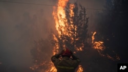 Un bombero ajusta su casco en la aldea de Varnava durante un incendio forestal, al norte de Atenas, Grecia, el domingo 11 de agosto de 2024, con muchas regiones del país en alerta máxima debido a las altas temperaturas y la velocidad del viento.