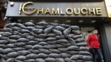 A Lebanese man walks past sand barriers that were set in front of a jewelry shop in a Shi&#39;ite neighborhood in a southern suburb of Beirut. After a wave of car bomb attacks on Hezbollah&#39;s stronghold south of Beirut that left scores of people dead or wounded over the past three months, shop owners scared of more bombs have set up sand barriers in front of their shops to reduce damage.
