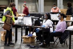 FILE - A GOP observer, left, watches as workers scan ballots as the Fulton County presidential recount gets under way at the Georgia World Congress Center in Atlanta, Nov. 25, 2020.
