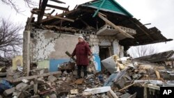 Liudmyla Momot weeps as she searches for any still-usable items Dec. 10, 2021, in the debris of her house in the village of Nevelske, Ukraine, after it was hit by a mortar shell fired by Russia-backed separatists. 