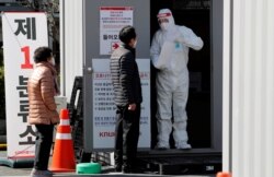 A medical worker in a protective gear offers consultation to people at the first stage screening post for checking for COVID-19 at Kyungpook National University Hospital in Daegu, South Korea, March 6, 2020.