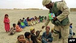 Американский солдат в деревне под Кандагаром угощает конфетами афганских детей.
