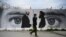 FILE - A man walks by a wall painted with images of U.S. Special Representative for Afghanistan Reconciliation Zalmay Khalilzad, left, and Taliban co-founder Mullah Abdul Ghani Baradar, in Kabul, April 5, 2020.