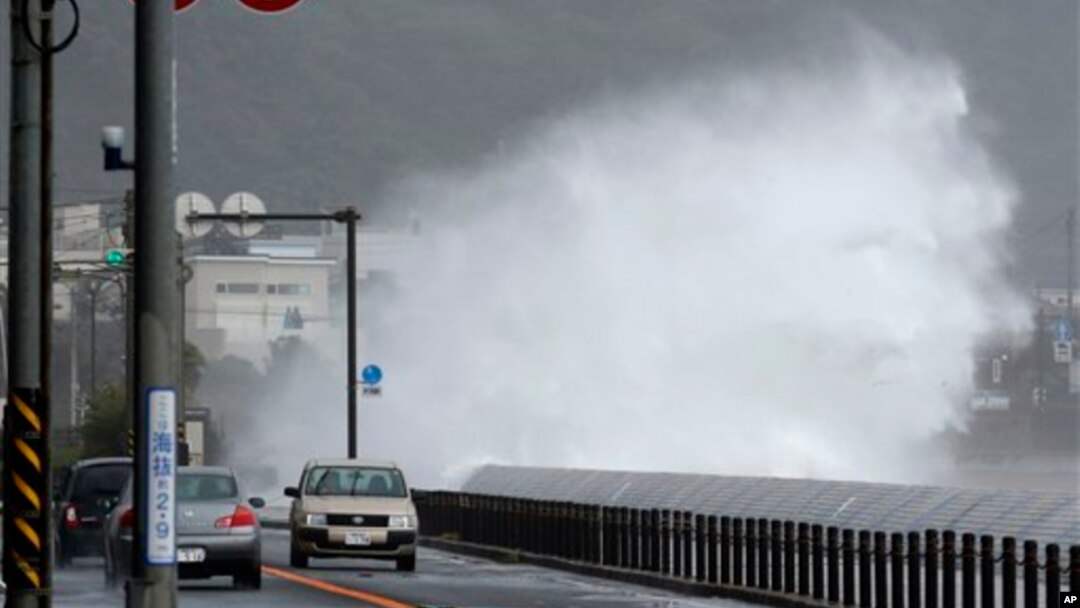 Mobil-mobil berjalan di samping ombak yang tinggi menjelang datangnya topan di Fujisawa, dekat Tokyo, Senin (16/9). (AP/Shizuo Kambayashi)