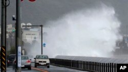 Mobil-mobil berjalan di samping ombak yang tinggi menjelang datangnya topan di Fujisawa, dekat Tokyo, Senin (16/9). (AP/Shizuo Kambayashi)