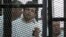 Al Jazeera's hunger-striking journalist Abdullah Elshamy stands behind bars with other prisoners at a court in Cairo, May 15, 2014.