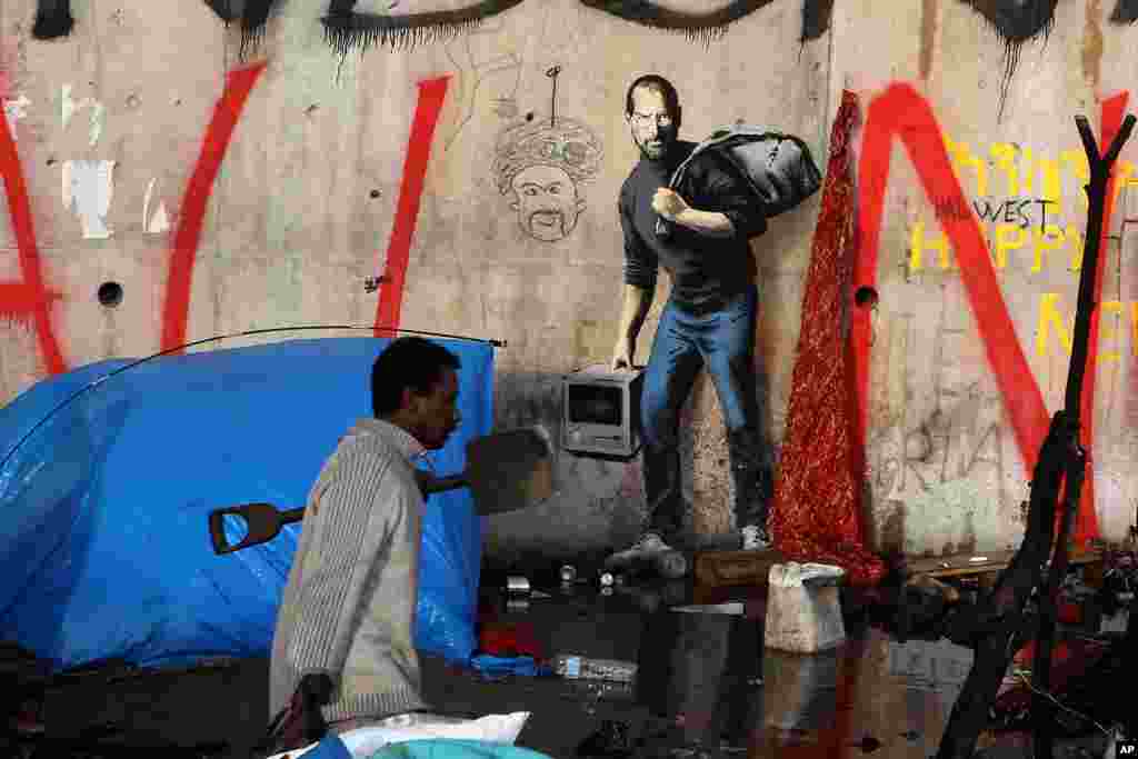 A migrant walks past a painting by English graffiti artist Banksy, at the entrance of the Calais refugee camp in Calais, northern France.