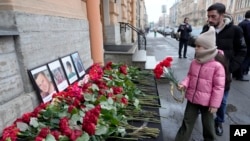 People lay flowers at the Consulate of Azerbaijan in the memory of victims of the Azerbaijan Airlines' Embraer 190 that crashed near the Kazakhstan's airport of Aktau, in St. Petersburg, Russia, Dec. 26, 2024.