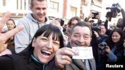 Juan Lopez holds his lottery ticket with the winning number of Spain's Christmas Lottery "El Gordo", together with his daughter Pilar in La Eliana near Valencia, Dec. 22, 2014.