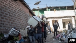 FILE—People carry a refrigerator from a house during a planned demolition in the historical Piazza neighborhood of Addis Ababa on March 17, 2024.