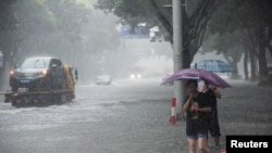 People holding umbrellas wade through floodwaters amid heavy rainfall on a street after Typhoon Lekima made landfall in Ningbo, Zhejiang province, China, Aug. 10, 2019. 