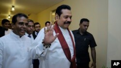 FILE - Sri Lanka's disputed Prime Minister Mahinda Rajapaksa gestures as he arrives for a meeting with his supporting lawmakers at the parliamentary complex in Colombo, Sri Lanka, Nov. 29, 2018.