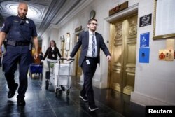 Polisi Capitol AS mengawal anggota staf Komite Penyelidik saat mereka mengangkut kotak dokumen setelah rapat komite untuk membahas pengembalian pajak mantan Presiden Donald Trump di Capitol Hill di Washington, AS, 20 Desember 2022. (REUTERS/Evelyn Hockstein)