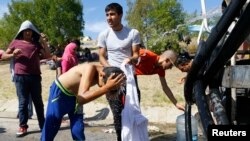 Seorang migran anak membasuh kepalanya dengan air di pinggiran jalan raya dekat Edirne, Turki, 17 September 2015 (foto: Reuters/Osman Orsal)