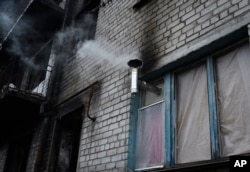 Stove pipe sticking out of boarded window in an apartment building in Lyman, Donetsk region, Ukraine, Nov. 18, 2022.