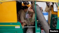 FILE - Aminbanu Memon wearing an oxygen mask sits in an autorickshaw waiting to enter a COVID-19 hospital for treatment, amidst the spread of the coronavirus disease (COVID-19) in Ahmedabad, India, April 28, 2021. 