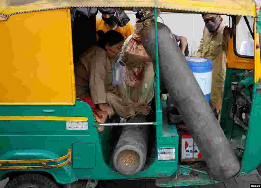 Aminbanu Memon wearing an oxygen mask sits in an auto-rickshaw waiting to enter a COVID-19 hospital for treatment in Ahmedabad, India.