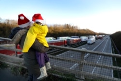 A mother and child look at the line of trucks parked up on the M20, part of Operation Stack in Ashford, Kent, England, Dec. 25, 2020.
