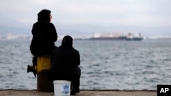 Two women sit on a dock of a refugee camp which houses about 3,200 refugees and migrants, in the western Athens' suburb of Skaramagas, Aug. 25, 2016. 