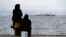 Two women sit on a dock of a refugee camp which houses about 3,200 refugees and migrants, in the western Athens' suburb of Skaramagas, Aug. 25, 2016. 