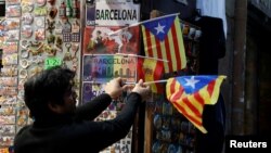 A shop keeper displays Catalan separatist "Estelada" flags next to souvenirs for tourists at a shop in Barcelona, Dec. 22, 2017. 