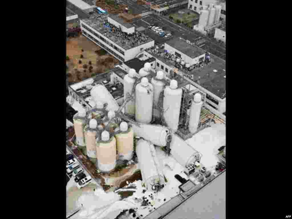 Evacuated employees are pictured near toppled tanks a brewery in Sendai, Miyagi Prefecture, northeastern Japan March 11, 2011. A massive 8.9 magnitude quake hit northeast Japan on Friday, causing many injuries, fires and a ten-metre (33-ft) tsunami along 