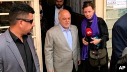 Iraq Prime Minister Haider al-Abadi, center, leaves a polling station after casting his ballot in the country's parliamentary elections in Baghdad, Iraq, May 12, 2018. 