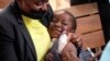FILE - A young girl smiles while been vaccinated against measles at a clinic in Harare, Zimbabwe, Thursday, Sept. 15, 2022. 