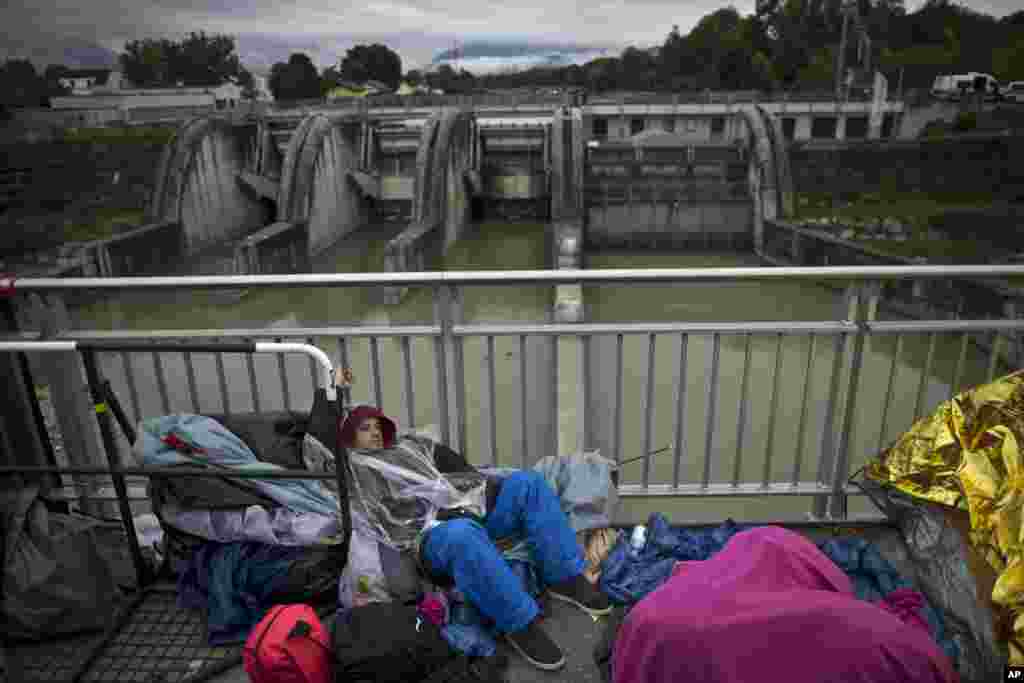 A Syrian refugee man rests on a bridge after he and other migrants spent the night waiting for their registration and transport by German police to a refugee shelter in Freilassing.