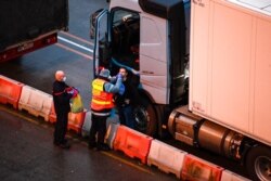 French officers give a COVID-19 test to a trucker at Dover, England, Dec. 24, 2020. Some freight from Britain and passengers with negative virus tests have begun arriving in France, after France relaxed a two-day blockade over a virus variant.
