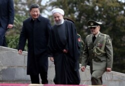 FILE - Chinese President Xi Jinping, left, is welcomed by Iranian President Hassan Rouhani during his official arrival ceremony at the Saadabad Palace in Tehran, Iran, Jan. 23, 2016.