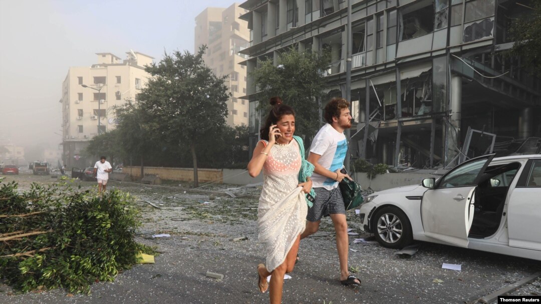 Personas corren para protegerse después de una explosión ocurrida en el puerto de Beirut.