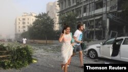 Personas corren para protegerse después de una explosión ocurrida en el puerto de Beirut.
