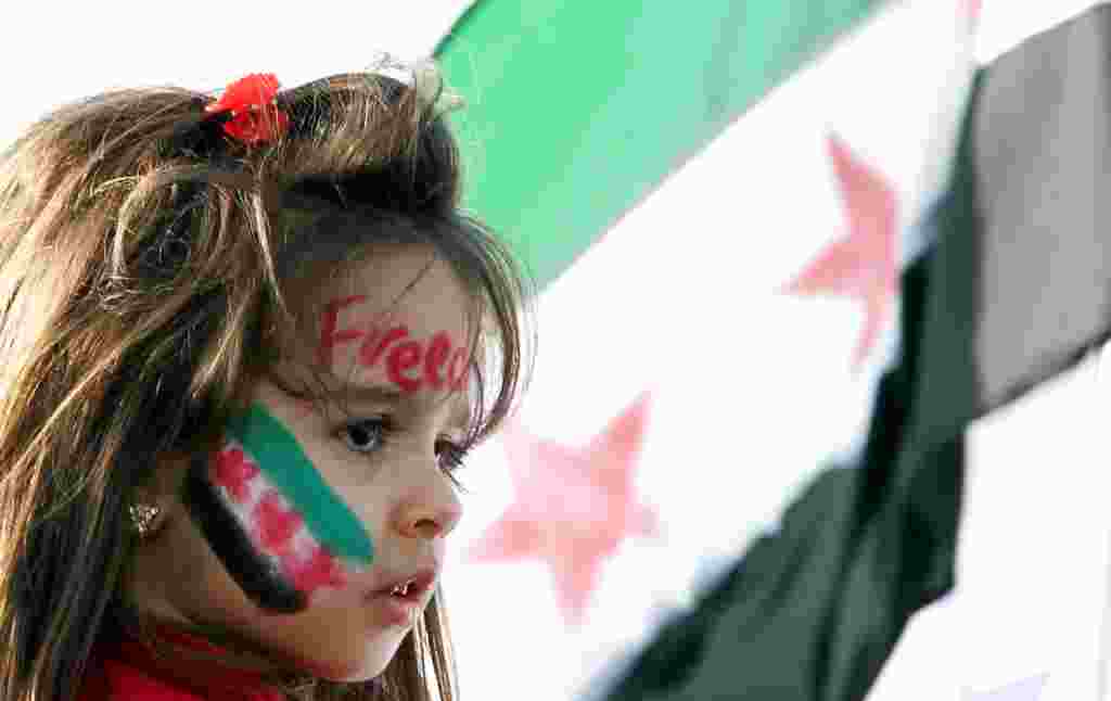 Seorang gadis cilik dengan gambar bendera revolusi Suriah dalam sebuah aksi protes di Doha, Qatar (AP).