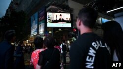 Para pejalan kaki menyaksikan penayangan berita dari layar raksasa di pusat kota Hong Kong, saat Pemimpin Hong Kong, Carrie Lam mengumumkan rencana pembatalan RUU Ekstradisi, 4 September 2019. 