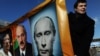 Opposition activists hold a banner with portraits of Russian Prime Minister Vladimir Putin, former Libyan leader Muammar Qaddafi and Belarus President Alexander Lukashenko at a rally in Pushkin Square, Moscow, in March of 2011. (AFP)