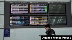 A man walks past a flight information board at Beijing’s Capital International Airport on Jan. 21, 2022. 